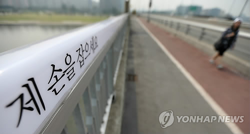 서울 마포대교에 써있는 자살예방 문구 옆으로 시민들이 지나가고 있다.