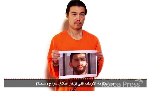 IS가 공개한 영상에 고토 겐지로 보이는 남성이 요르단 중위 유세프 아카사스베로 추정되는 인물의 사진을 들고 있는 모습